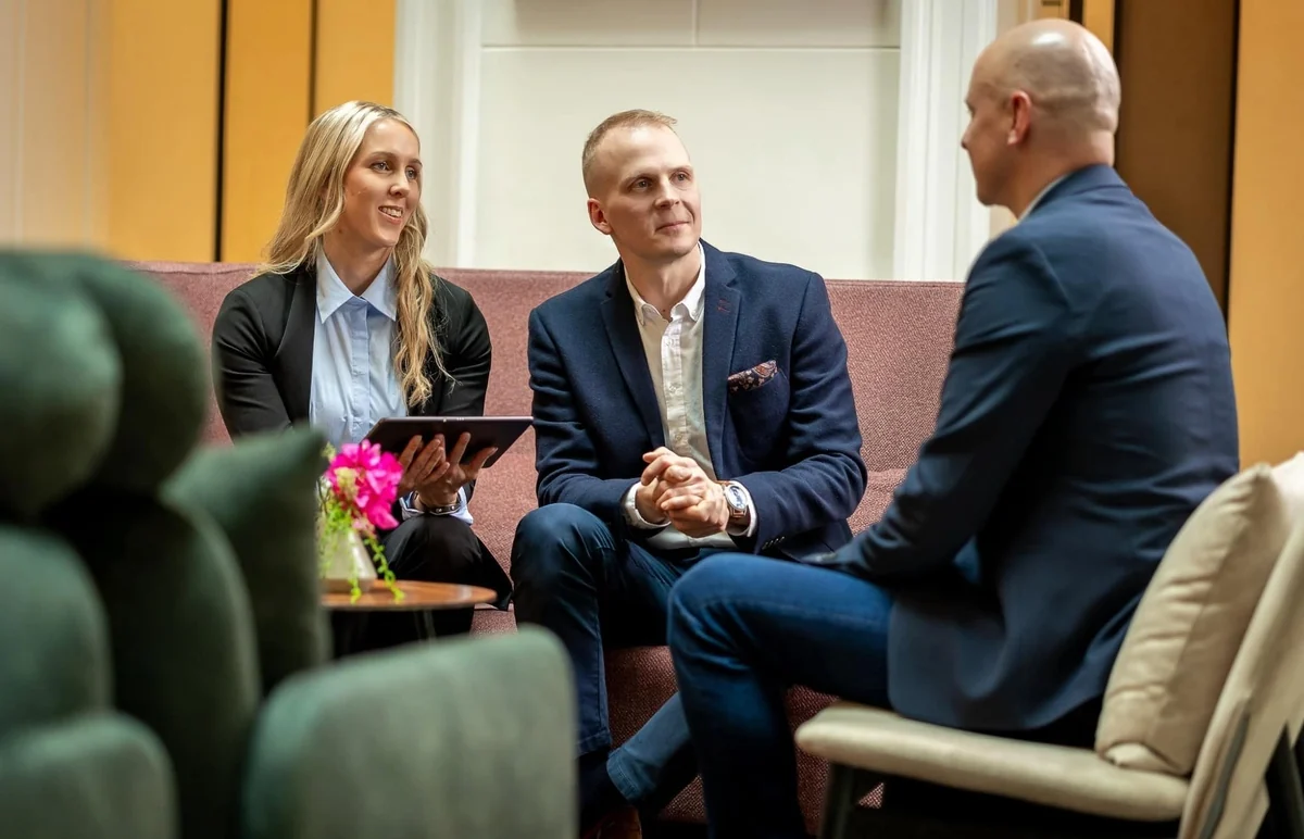 Kolme ihmistä keskustelemassa työtapaamisessa.